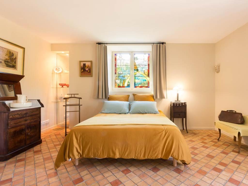 ein Schlafzimmer mit einem Bett mit gelber Bettwäsche und einem Fenster in der Unterkunft Le Moulin de la Maison des Templiers in Saint-Cernin-de-Larche