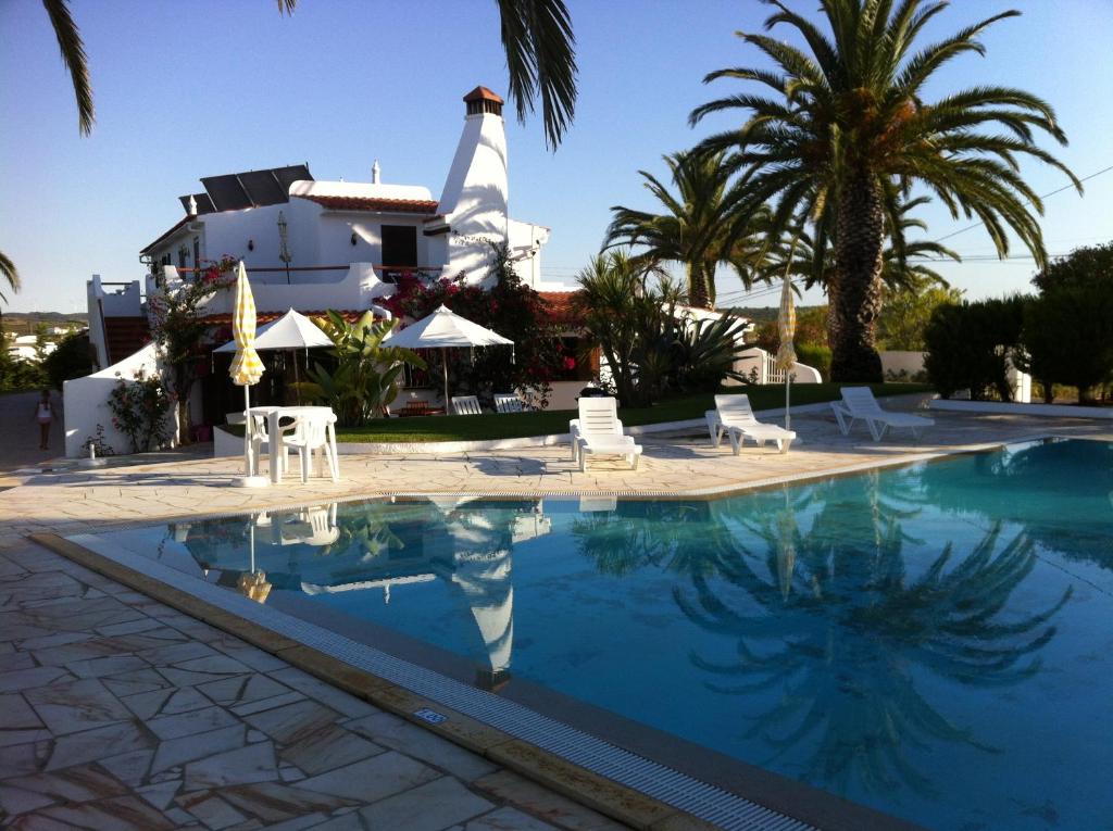 una piscina di fronte a una casa con palme di RÉSIDENCE LES ARCADES ad Almádena