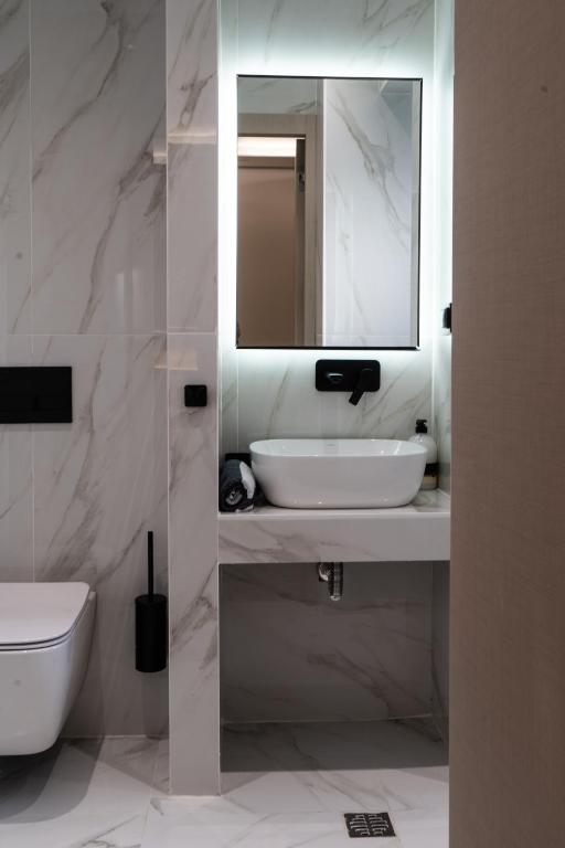 a white bathroom with a sink and a mirror at NERO SEASCAPE SUITES in Fanari