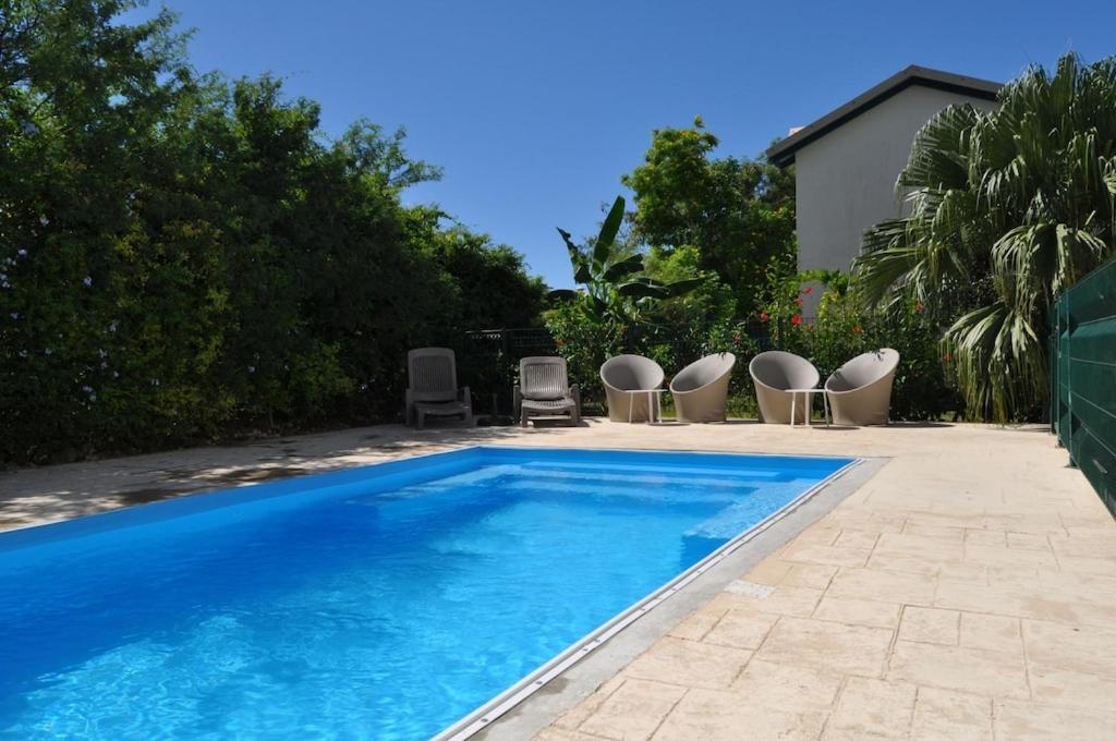 una piscina con sedie e una piscina di Villa avec piscine privée, calme, proche des plages, à Sainte Anne a Sainte-Anne