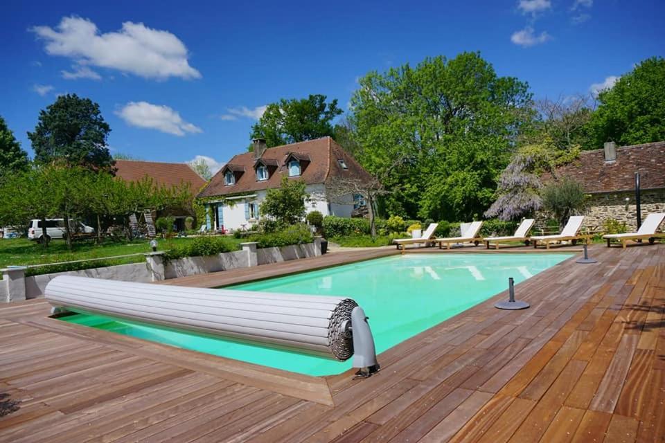 une piscine avec une terrasse en bois et une maison dans l'établissement Domaine du Mas Coutant, à Sarlande