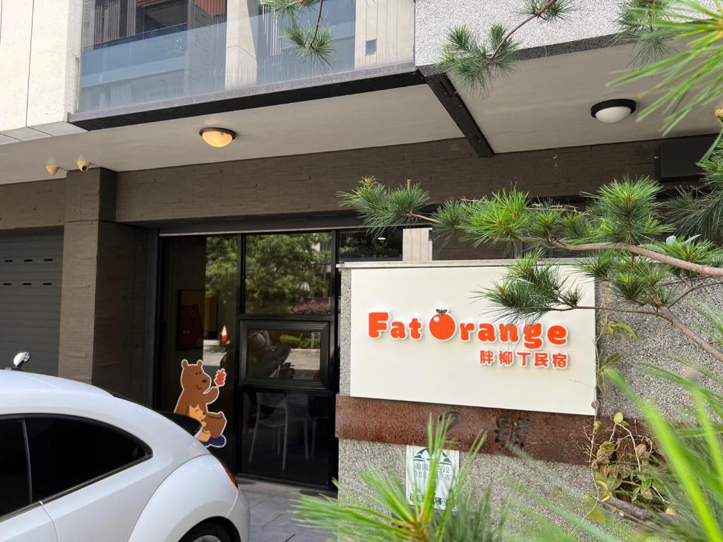 een auto geparkeerd voor een gebouw met een oranje bord bij Flying Orange Homestay in Luodong