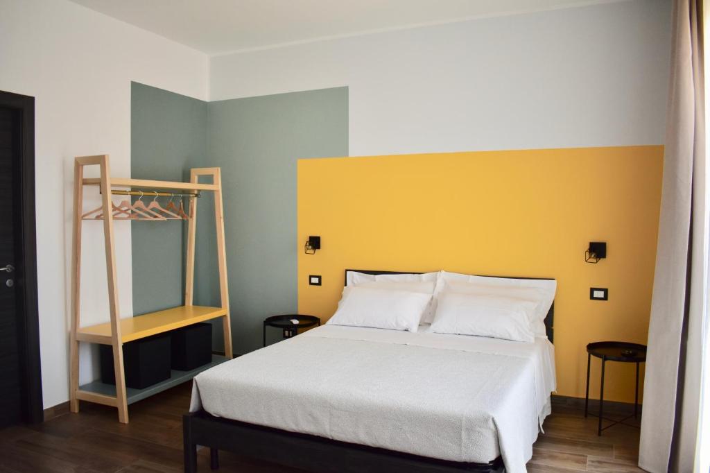 a bedroom with a bed with a yellow headboard and a ladder at Domus Solis in Pachino
