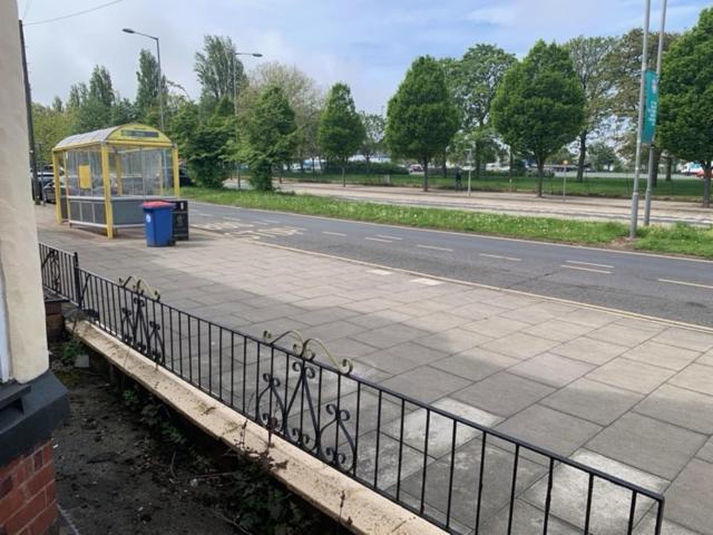 a bus stop with a fence next to a street at Anfield view in Liverpool