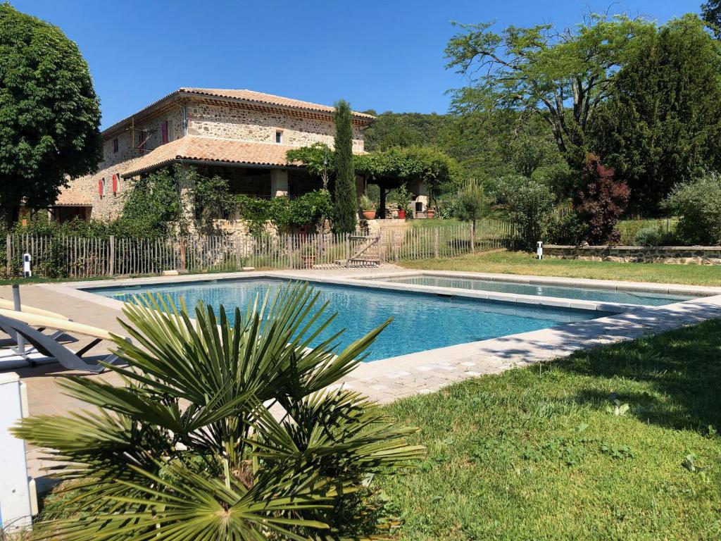 ein Schwimmbad mit einem Haus im Hintergrund in der Unterkunft Le Mas du Martinet in Anduze