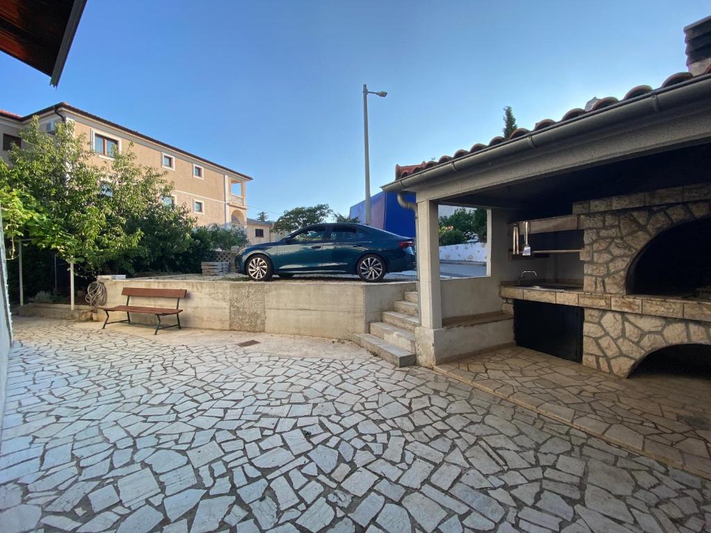 une voiture garée à côté d'un bâtiment avec une terrasse en pierre dans l'établissement Apartment Bigi, à Novi Vinodolski