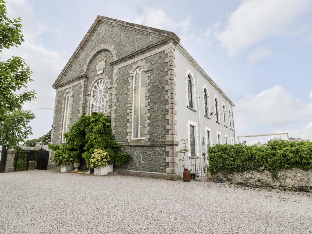 an old stone church with a gravel driveway at Capel Mawr, Basement 19 in Caernarfon