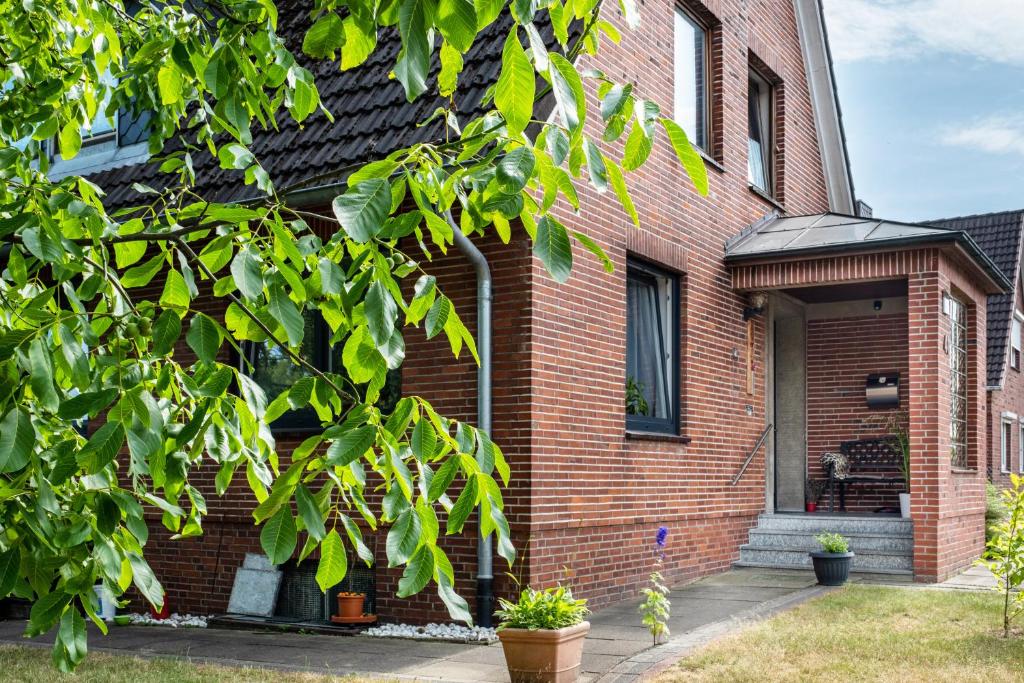 une maison en briques avec un arbre devant elle dans l'établissement Ferienwohnung am Elbstrom, à Stade