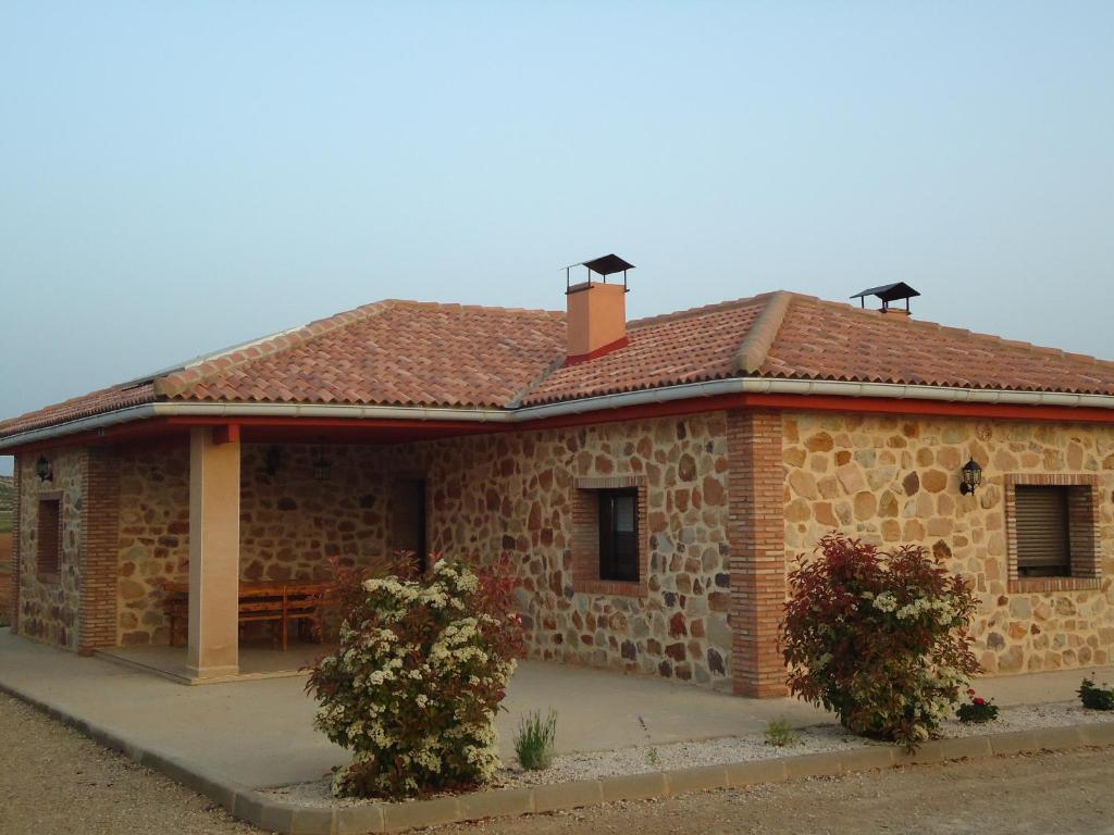 una pequeña casa de piedra con techo y dos arbustos en Casa Rural Escapada Rústica Teruel, en Teruel