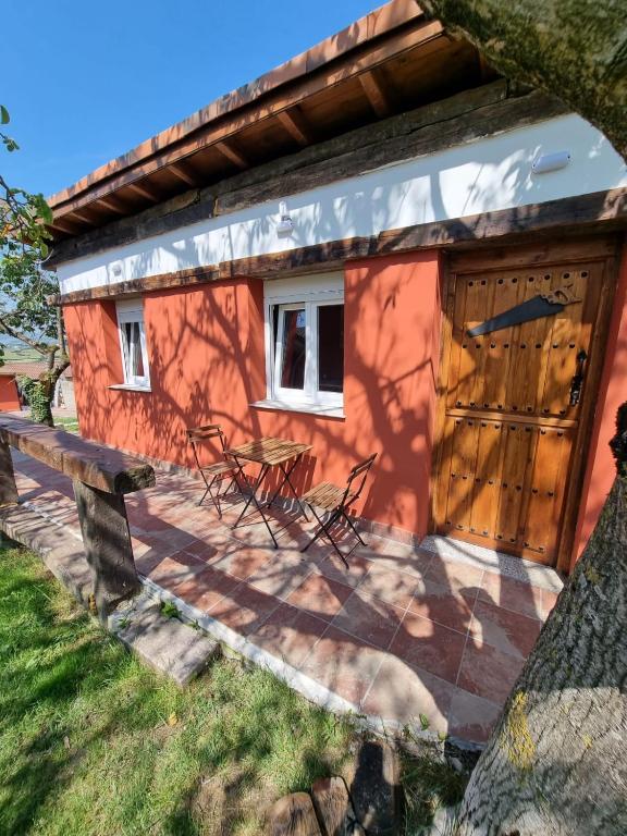 un pequeño edificio rojo con puerta de madera en Alojamiento con finca en Gijón 