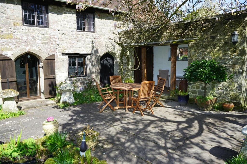a table and chairs in front of a stone house at Character 2 double bedroom cottage in Shaftesbury in Shaftesbury