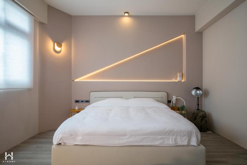 een slaapkamer met een wit bed met een licht erboven bij Coming Home in Yilan