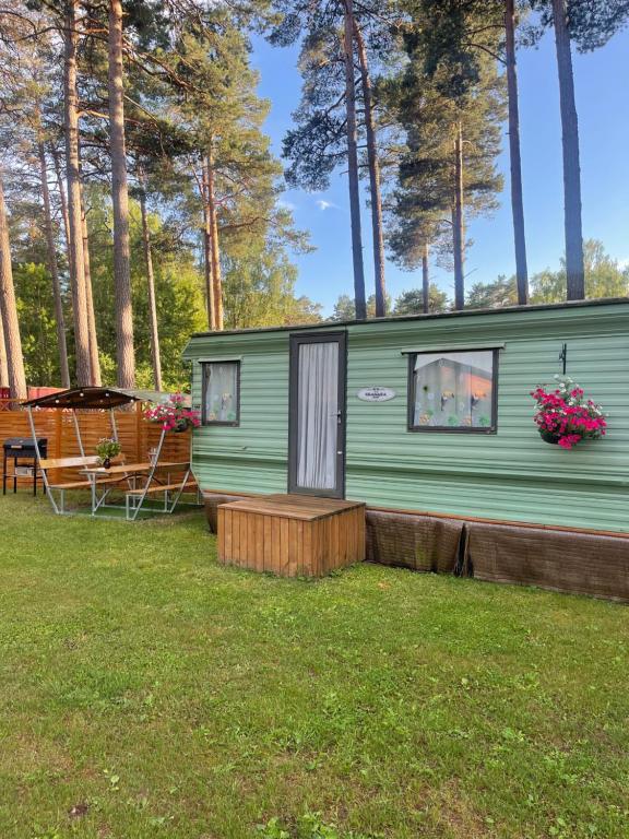 a green tiny house with a porch and a deck at Summer beach house in Saulkrasti