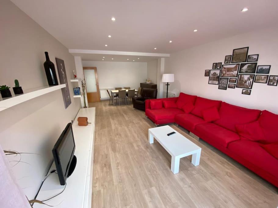 a living room with a red couch and a tv at Piso céntrico recién reformado in Torredembarra