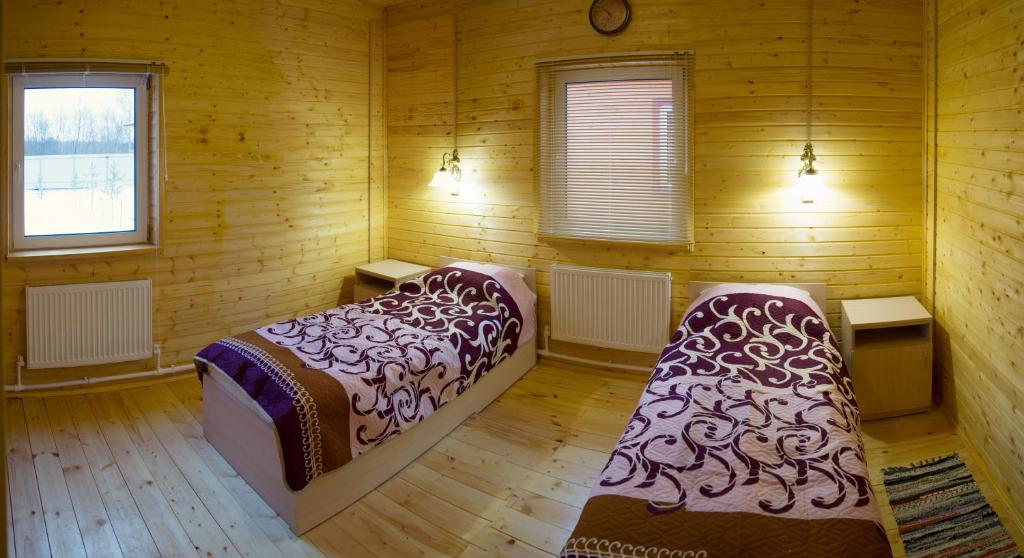 a bedroom with two beds in a wooden room at Ramanov Plyos Guest House in Vladimir