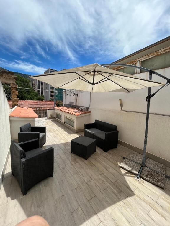 een patio met een parasol en stoelen op een dak bij La Girandola in Palermo