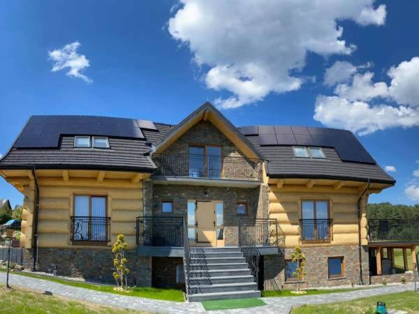 a large wooden house with a black roof at SASÓWKA APARTAMENT in Maniowy
