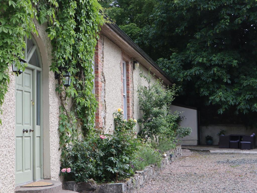 an ivy covered building with a door and flowers at Millvale Cottage in Cootehill