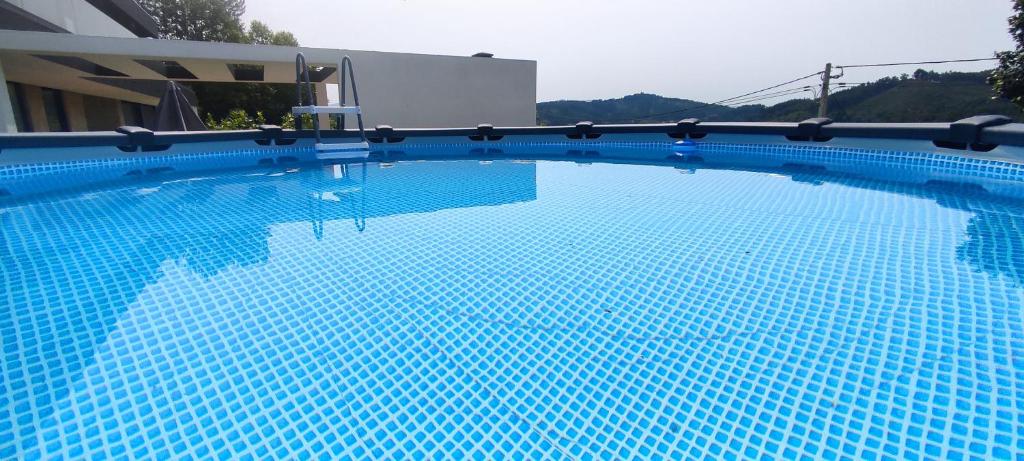 een groot zwembad met blauw water voor een gebouw bij Casa de Silvares in Celorico de Basto