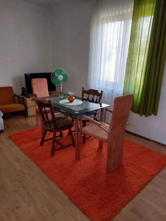 ein Esszimmer mit einem Tisch und Stühlen auf einem Teppich in der Unterkunft Raj in Bela Crkva