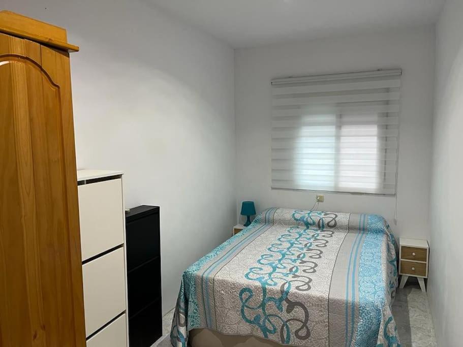 a small bedroom with a bed and a window at Casa Denise in Playa de Gandia