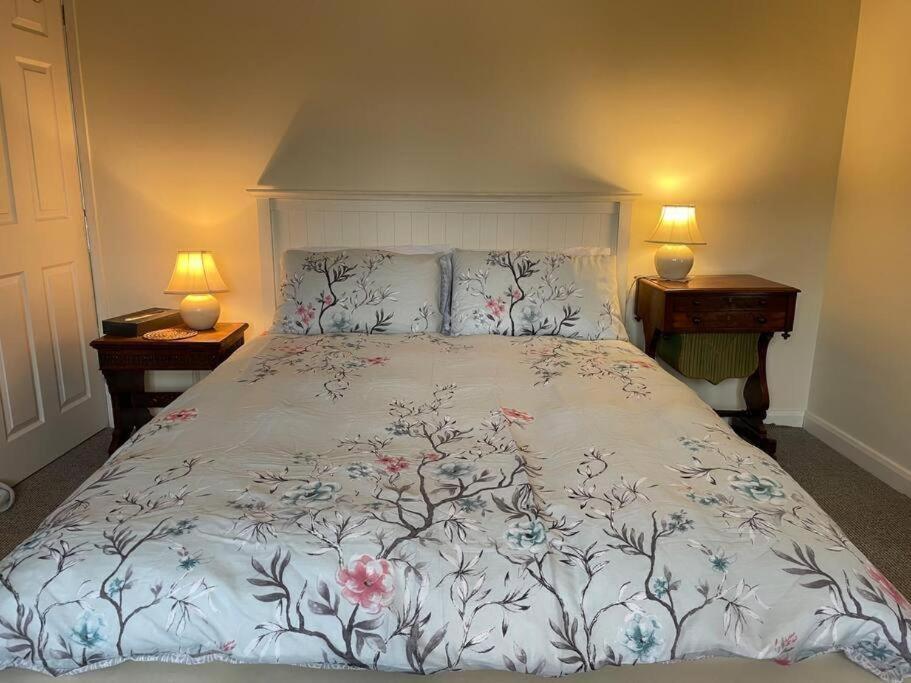 ein Schlafzimmer mit einem großen Bett mit Blumen darauf in der Unterkunft Manor Farm Holiday Cottages in Chard