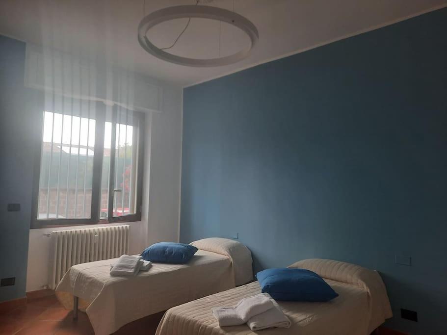 een kamer met 2 bedden, blauwe muren en een raam bij GROSSI 19 in Rho