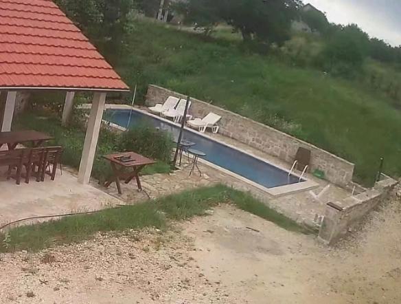 uma piscina com mesa e cadeiras e uma casa em Vir em Nikšić