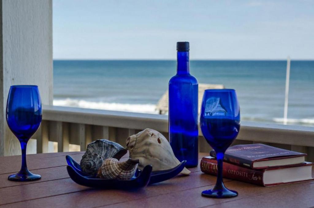a table with two blue glasses and a bottle of wine at SC302 - C-View in Kill Devil Hills