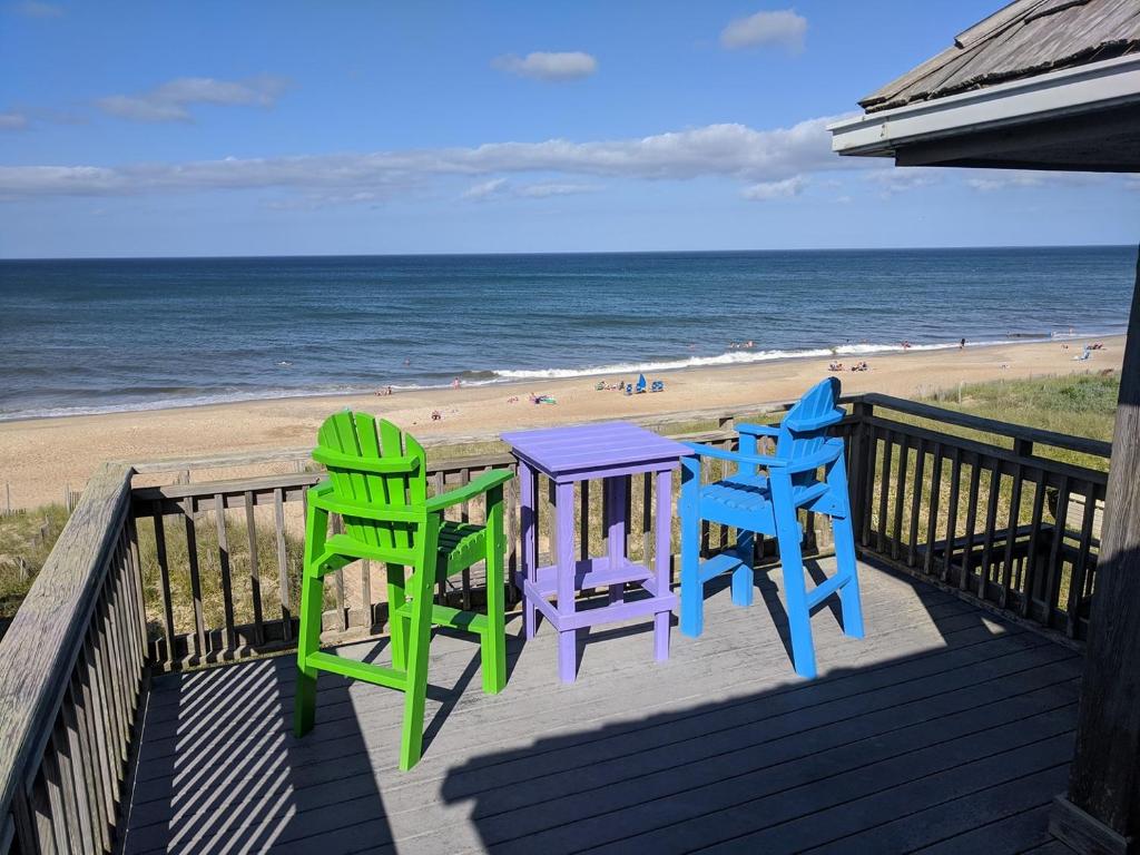 a deck with two chairs and a table on the beach at SS9 - Raynorshine in Kill Devil Hills