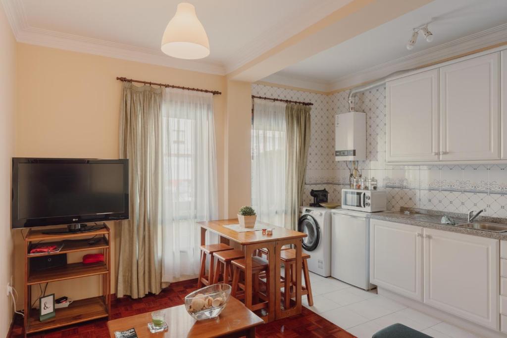 cocina con TV y mesa en una habitación en Rising Sun Apartment en Leça da Palmeira