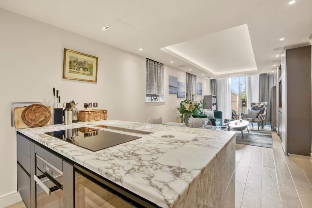 uma cozinha com uma bancada em mármore e uma sala de estar em Canal Side Luxury 1 Bed Chelsea em Londres