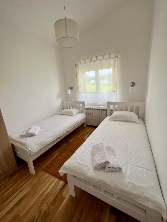 two beds in a small room with a window at Divine House in Žabljak