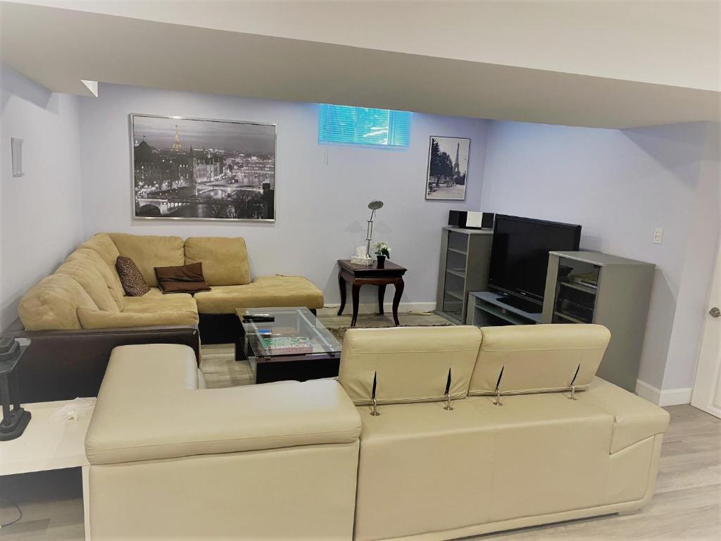 a living room with two couches and a tv at Gilford Beach Apartment in Innisfil