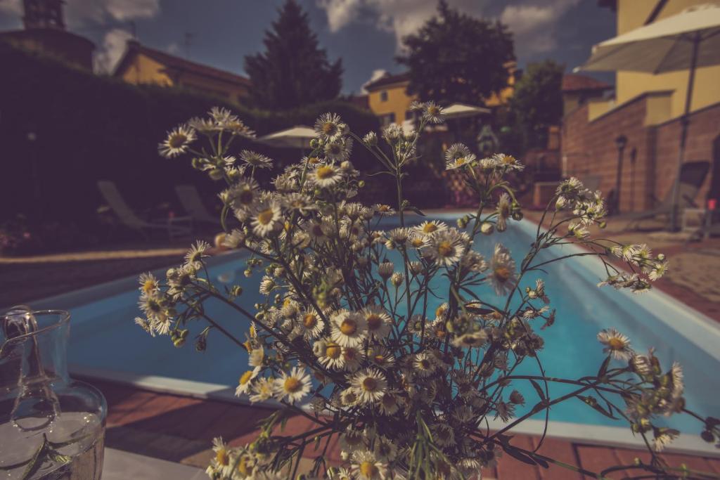 un vase de fleurs assis sur une table à côté d'une piscine dans l'établissement Agriturismo I Surì Asti, à Asti