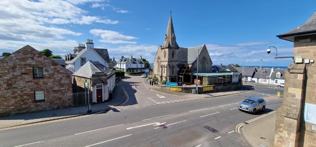 una piccola città con una chiesa e un'auto in strada di Colin Young Place a Nairn