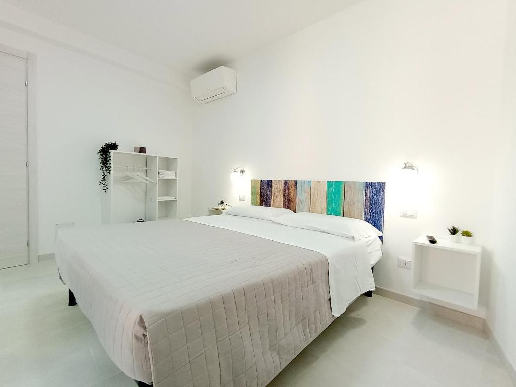 a white bedroom with a large white bed in it at Monolocali Cavour - Affitti Brevi Italia in Ulassai