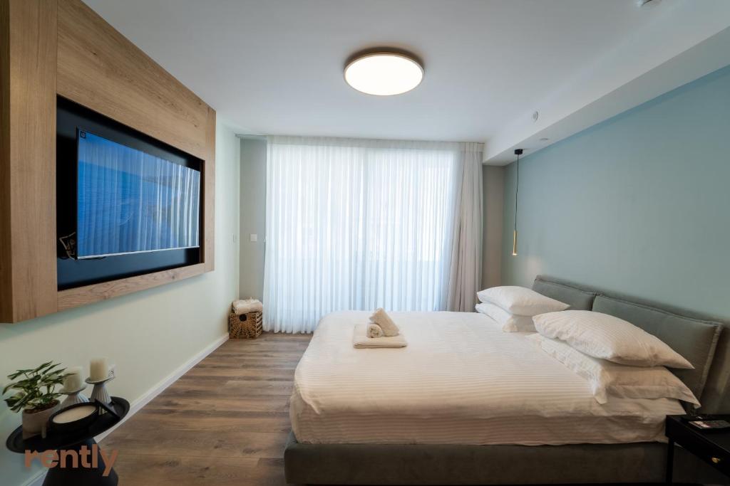 a bedroom with a large bed and a flat screen tv at Sea side "Tulip" apartment - by Rently in Eilat