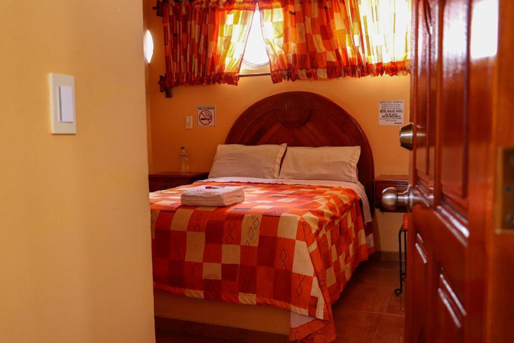 a bedroom with a bed with a checkered blanket at HOTEL MIGUEL ÁNGEL in Progreso de Obregón