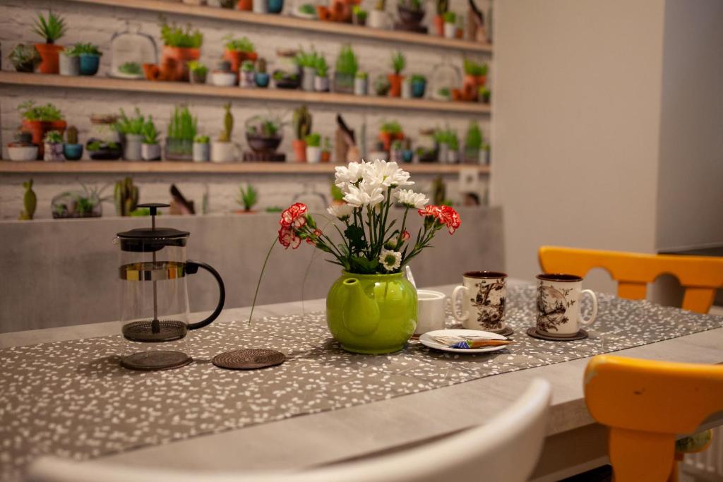 a table with a green vase with flowers on it at Lukas Guest Rooms in Kraków