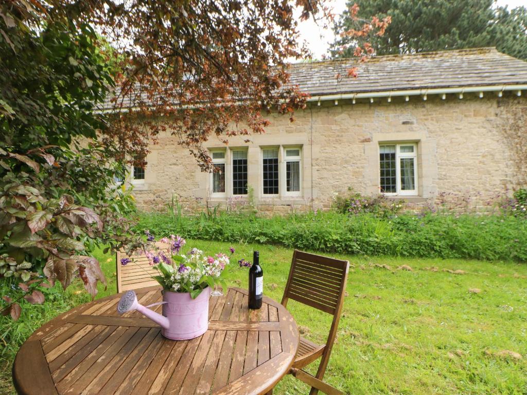 a wooden table with a bottle of wine and flowers on it at The Coach House in Ridingmill