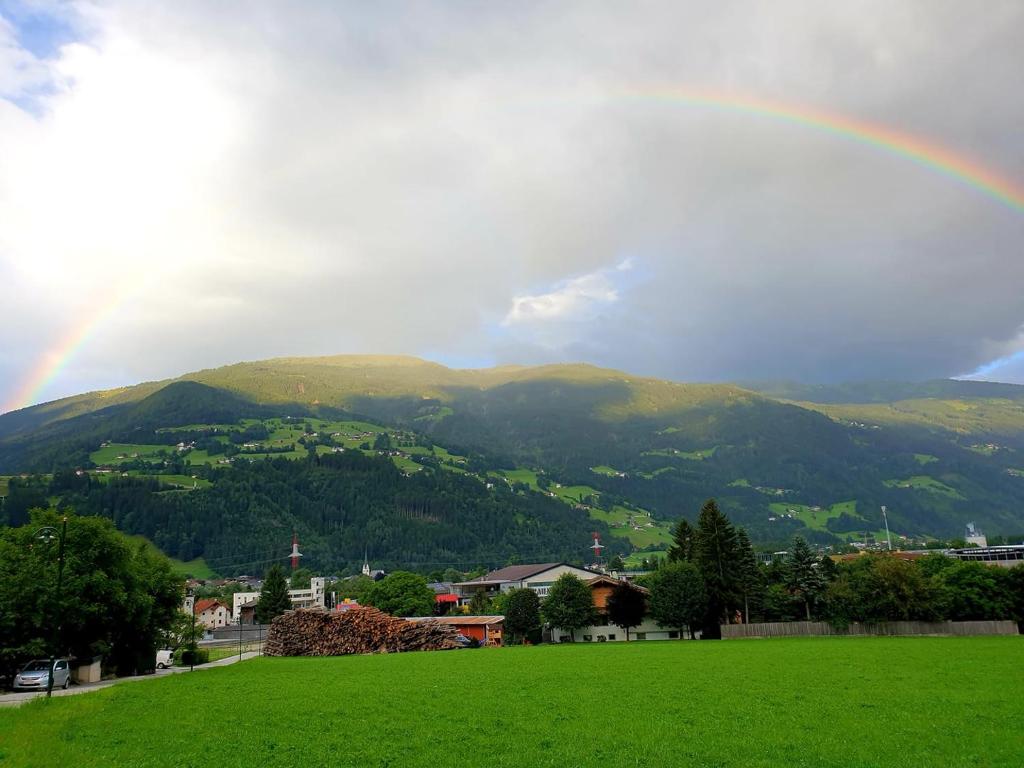un arcobaleno su un campo verde con una montagna di Ferienwohnung Ursprung Zillertal a Kaltenbach