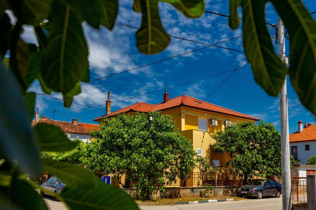 une maison jaune avec un toit rouge dans une rue dans l'établissement Nikola apartments free parking BBQ, à Zadar