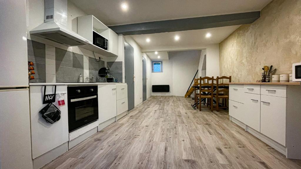 a kitchen with white cabinets and a wooden floor at Maisons de vacances 3 lits in Varzy