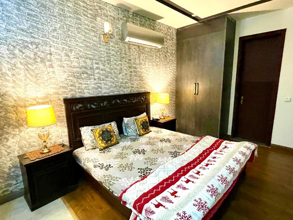um quarto com uma cama, 2 candeeiros e uma parede de tijolos em Entire Studio Apartment em Islamabad