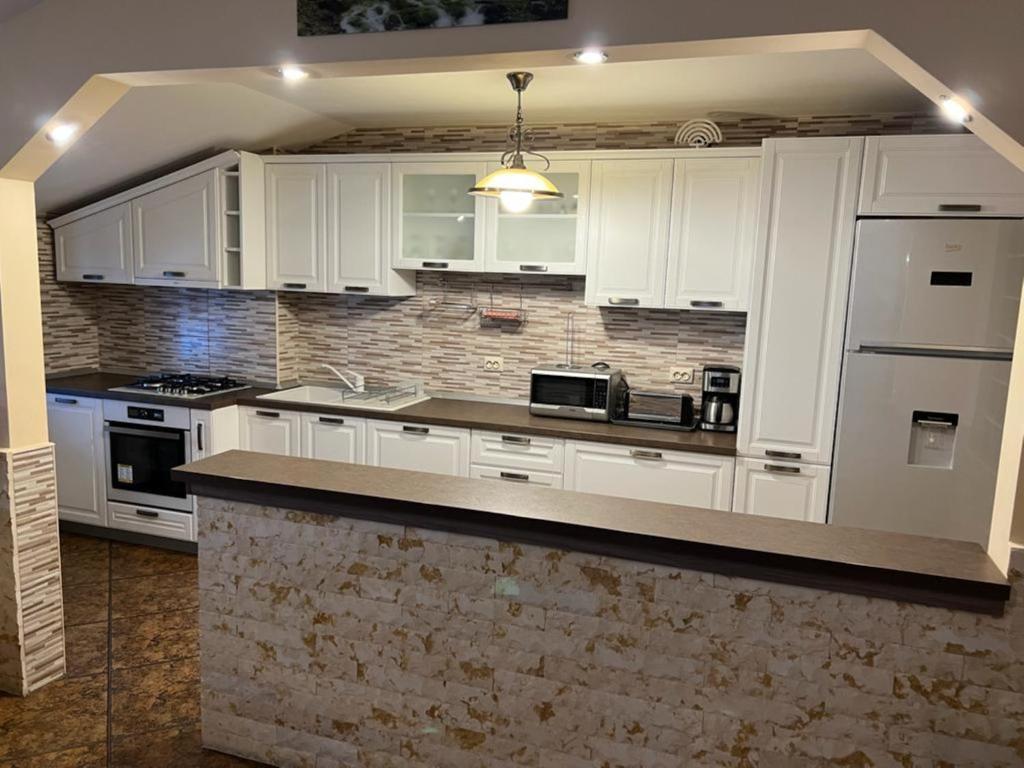 a kitchen with white cabinets and a brick wall at Apartament Darius in Moieciu de Sus