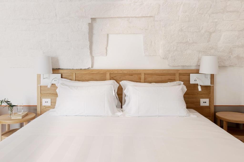 a bedroom with a white bed with white pillows at Masseria Auraterrae in Polignano a Mare