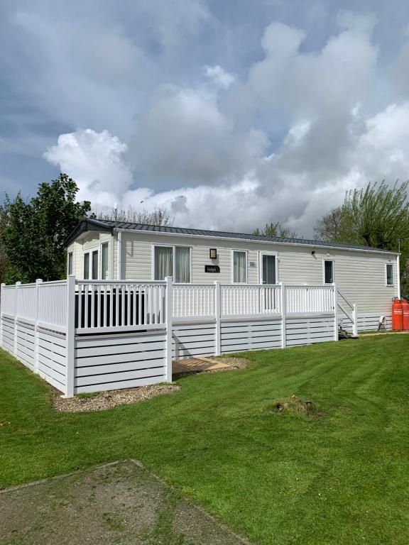 a white house with a fence in a yard at Meadows 3 NEW BEACH HOLIDAY PARK in Dymchurch