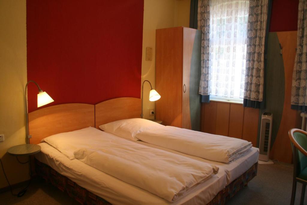 two beds in a bedroom with two lights on at Hotel Cafe Lieb in Bamberg