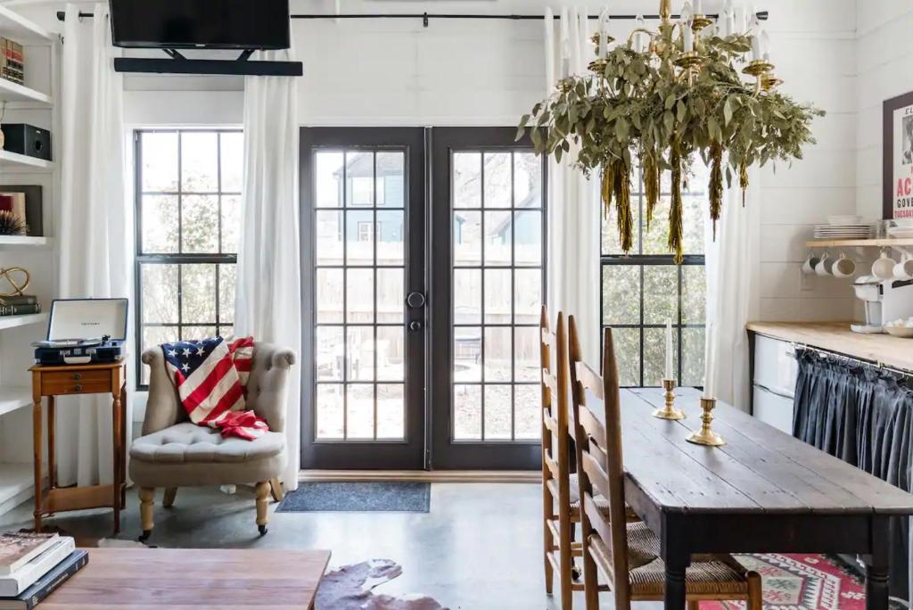 a dining room with a wooden table and chairs and windows at Hip, Cozy Cottage with a Fire Pit in Cleveland Park in Nashville